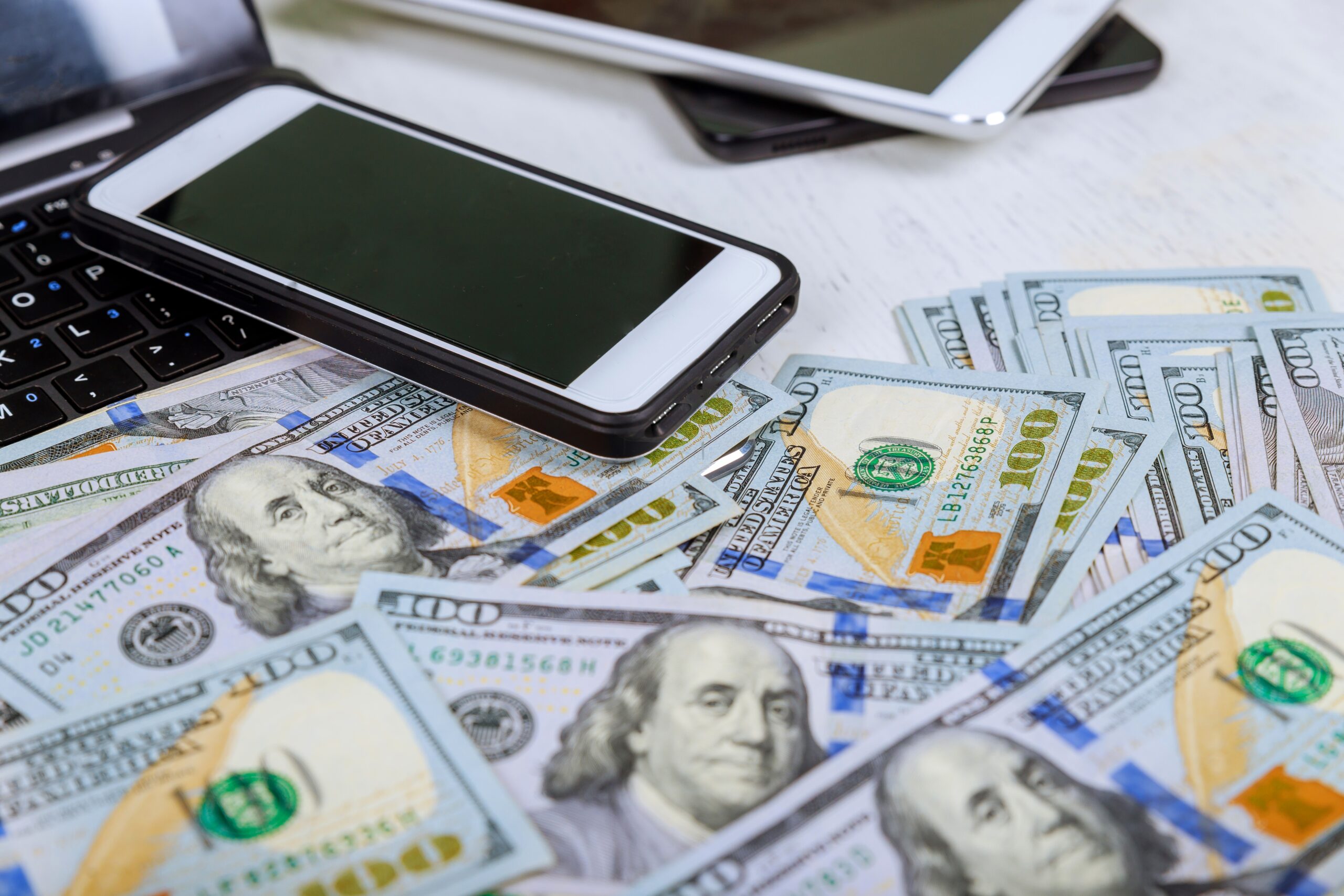 Mobile phone and US dollar banknotes on keyboard of notebook. Concept of payment and savings.