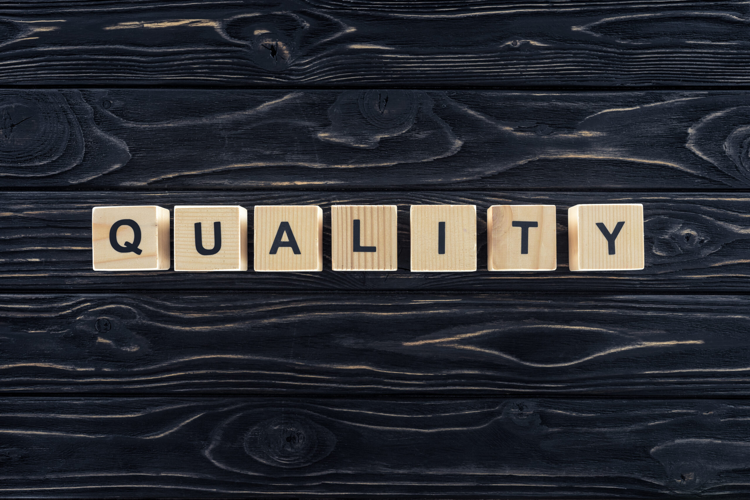 top view of word quality made of wooden blocks on dark wooden tabletop